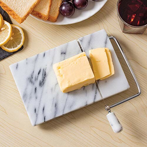 Marble butter slicer with butter, bread, grapes, and drink.