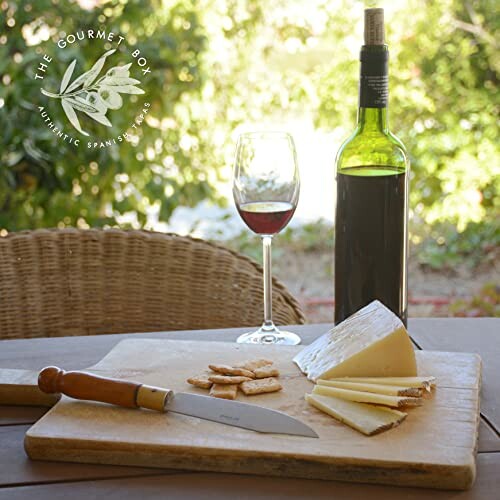 Outdoor table with wine, cheese, and crackers.